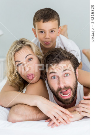Portrait of parents and son lying on bed and having fun 24216829