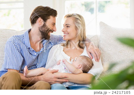 Parents sitting on sofa with their child 24217105