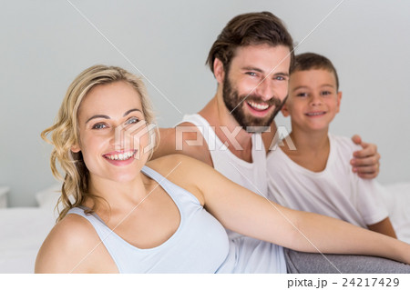 Portrait of parents and son sitting on bed in bedroom 24217429