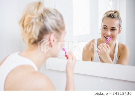 Young woman brushing teeth in bathroom 24218436