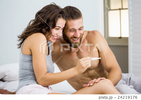 Happy couple looking at pregnancy test on bed Happy couple looking at pregnancy test on bed 24219176
