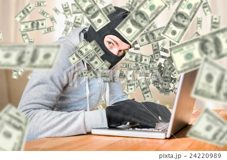 Composite image of focused thief with hood typing on laptop 24220989