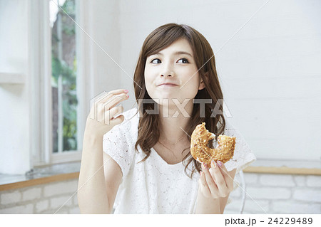 ドーナッツを美味しそうに食べる若い女性の写真素材 ドーナッツを美味しそうに食べる若い女性の写真素材