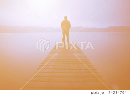 Man Standing on a Jetty by Tranquil Lake Man Standing on a Jetty by Tranquil Lake 24234794