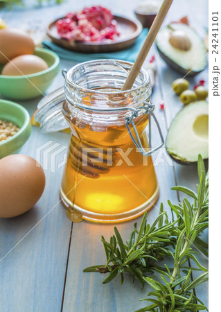 Jar of honey with dipper and fresh herbs 24241101