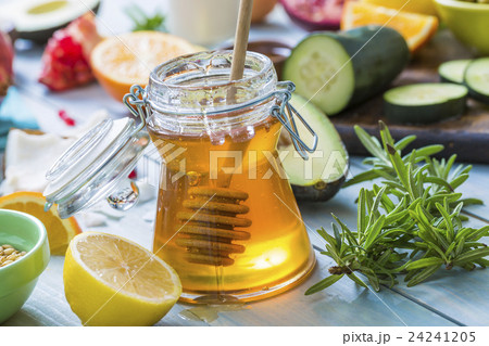 Jar of honey with dipper, lemon and fresh herbs 24241205