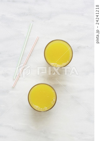 Overhead view of glass of orange juice and drinking straws 24241218