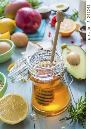 Jar of honey with dipper and fresh fruits and herbs 24241241