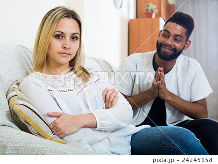 Indoors portrait of mixed couple trying to reconcile after quarrel Indoors portrait of mixed couple trying to reconcile after quarrel 24245158