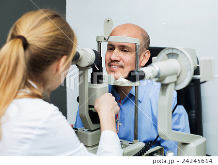 Friendly female optician doing eye examination with lamp 24245614