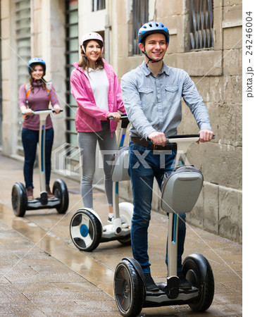 Laughing friends posing on segways on city street 24246004