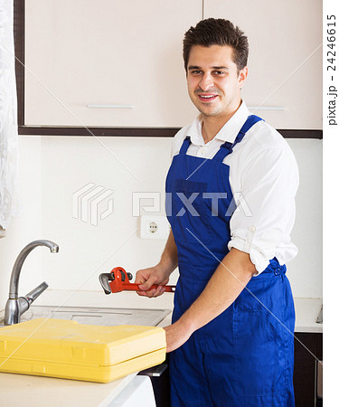 Professional plumber fixing problems in domestic kitchen 24246615