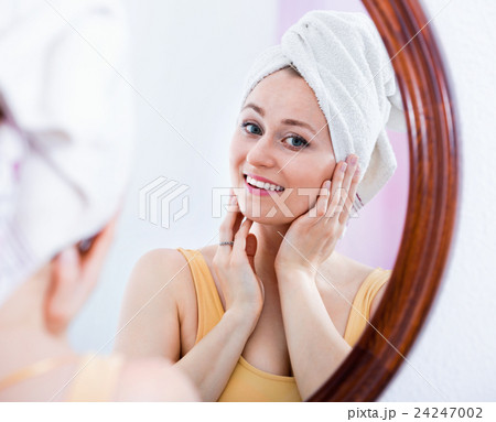 Woman came from the shower and standing next to the mirror 24247002