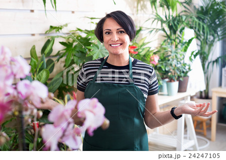 Glad woman florist smiling among the potted plants Glad woman florist smiling among the potted plants 24247105