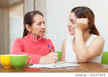 Two serious women fills in documents 24247859