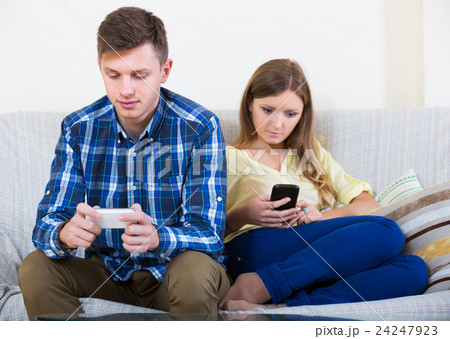 Spouses sitting with smartphones Spouses sitting with smartphones 24247923