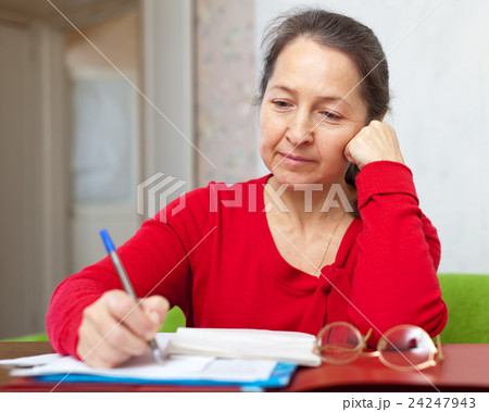 serious mature woman fills in documents 24247943
