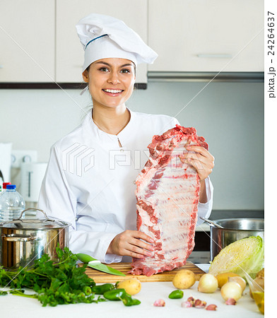 Positive female chef working with pork ribs 24264637