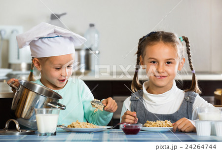Two small happy girls eating healthy oatmeal Two small happy girls eating healthy oatmeal 24264744