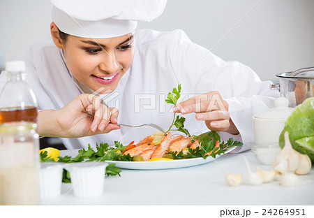 Professional female cook decorating prepared dish of shrimps 24264951