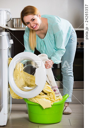 Portrait of housewife with bed linen near washer 24265357