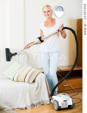 blonde in casual using domestic hoover during clean-up 24265469