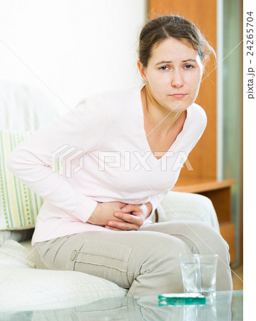 Portrait of girl folding up with belly pain indoor Portrait of girl folding up with belly pain indoor 24265704