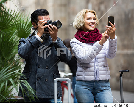 couple walking with luggage, camera and smartphone couple walking with luggage, camera and smartphone 24266406