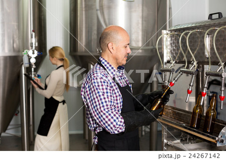 Man employee bottling beer in glass bottles 24267142