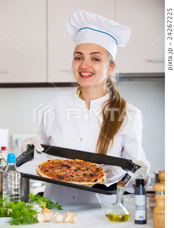 Happy female cook holding tray with pizza Happy female cook holding tray with pizza 24267225