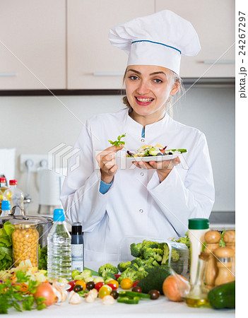 Positive chef decorating salad with parsley in kitchen 24267297