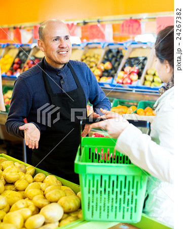 Friendly worker selling vegetables to female customer 24267382