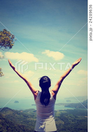 young successful woman open arms on mountain peak 24289636