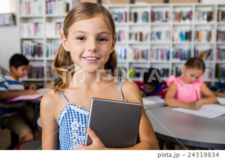 A cute little girl smiling at the camera with tablet pc 24319834