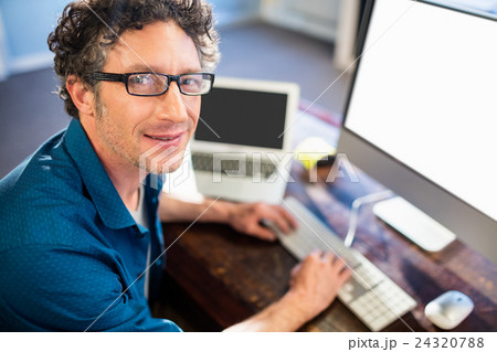 Smiling businessman working on computer 24320788