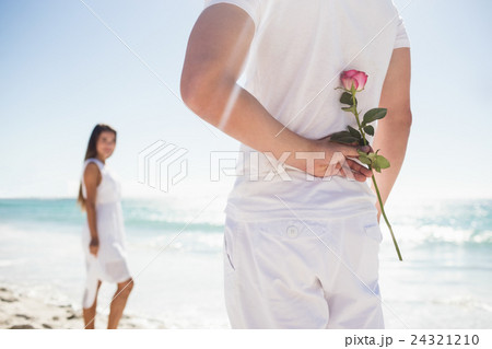 Close up of man holding a rose behind him Close up of man holding a rose behind him 24321210