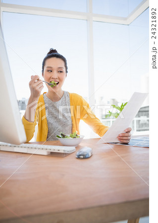 A beautiful businesswoman eating and reading 24321892