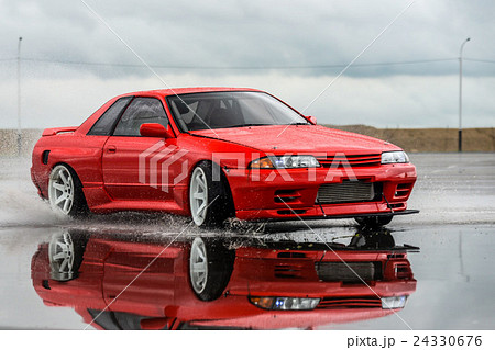 Nissan skyline R 32 red color on a wet road Nissan skyline R 32 red color on a wet road 24330676