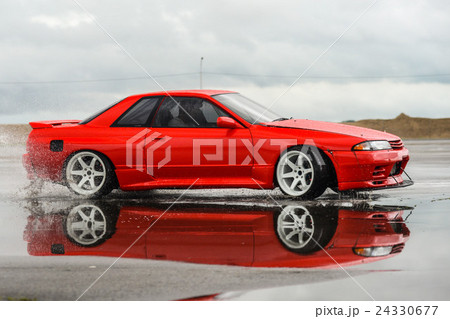 Nissan skyline R 32 red color on a wet road Nissan skyline R 32 red color on a wet road 24330677