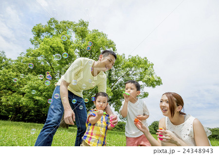 公園でシャボン玉遊びをする4人家族の写真素材