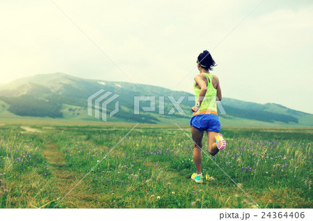 young woman runner running on trail in grassland young woman runner running on trail in grassland 24364406