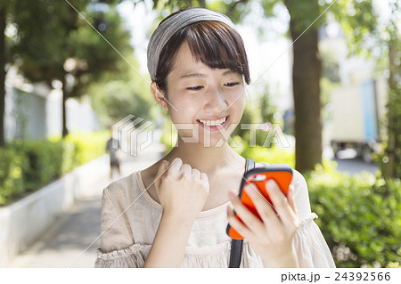 若い女性　スマホ　操作　ガッツポーズ　休日　ライフスタイル　通り　渋谷区　代官山 24392566