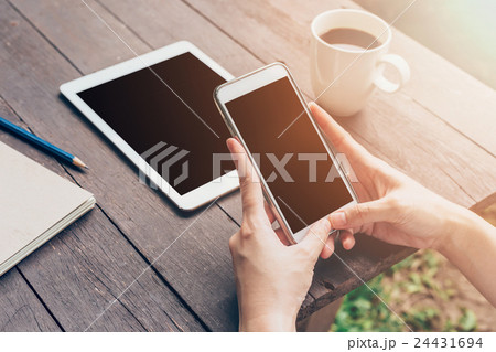 Woman hand holding phone and using phone on table Woman hand holding phone and using phone on table 24431694