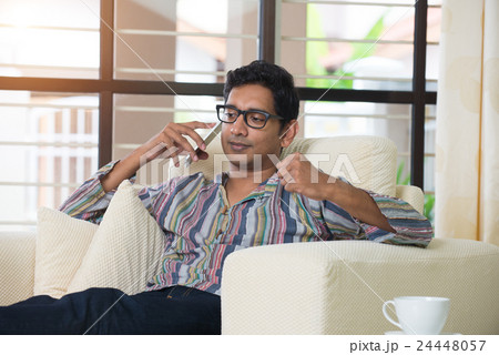 casual indian male with phone on sofa casual indian male with phone on sofa 24448057
