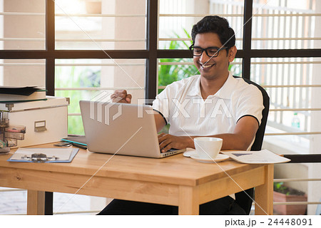 young indian man celebrating success while working young indian man celebrating success while working 24448091