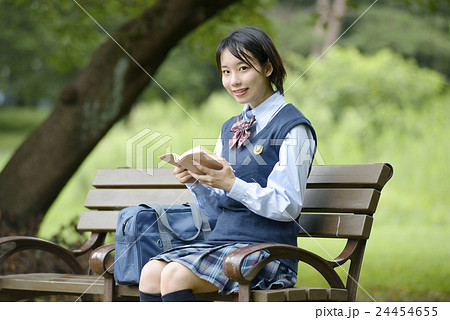 ベンチに座って本を読む女子高校生の写真素材