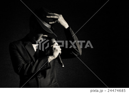 Songer hand holding the microphone and singing on black background, musical concept 24474685
