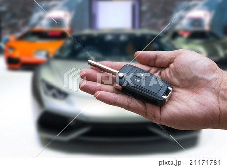 Man hand holding and giving a car key remote on photo blurred of car for buy, technology safety transportation concept Man hand holding and giving a car key remote on photo blurred of car for buy, technology safety transportation concept 24474784