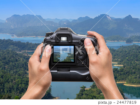 Hands holding the camera which taking photo of Mountain landscape from View point at Khaosok National Park, Ratchaprapha Dam, Thailand 24477819