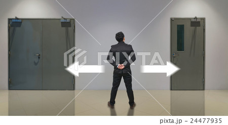 Businessman standing in doubt,thinking the two different choices indicated by arrows pointing in opposite direction, business decision concept 24477935